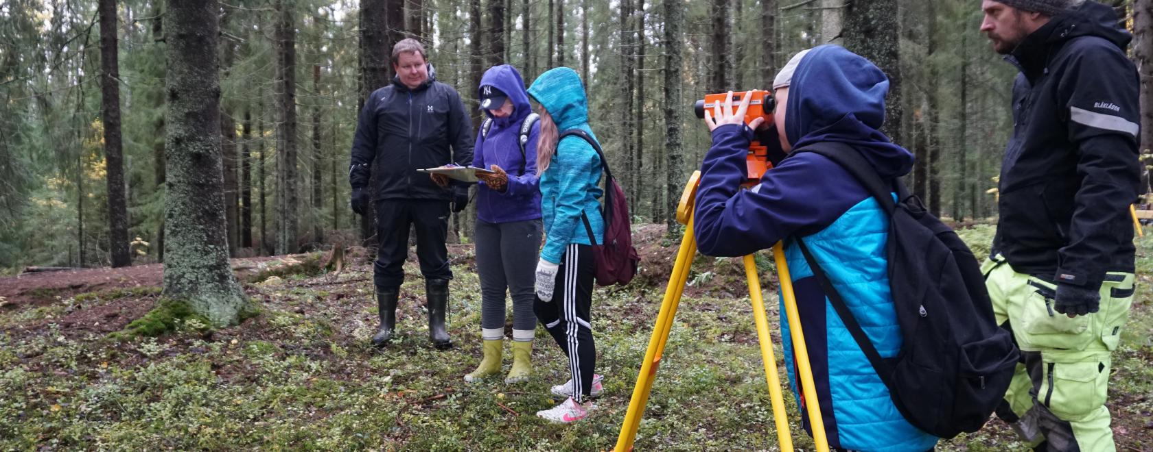 Arkeologi Jan-Erik Nyman (edessä) opasti nuoria mittauslaitteiden käyttöön. Taustalla myös Ähtärin yhteiskoulun rehtori Markku Juhola. 